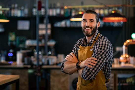 Manchester-cafebar-owner-550x367 Man in apron standing confidently.
