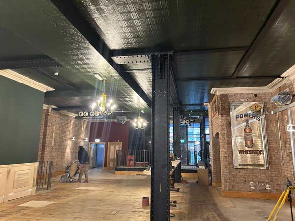 classic-building-group-interior-freemount Flooring team fitting preparing hard wood flooring with a sander in the bar interior during restaurant fit-out
