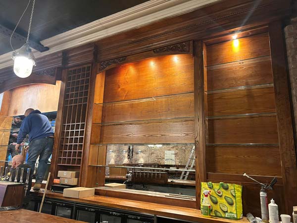 classic-building-group-polished-bar-manchester (2) Joiner installing bespoke timber shelving during commercial bar fit-out in manchester
